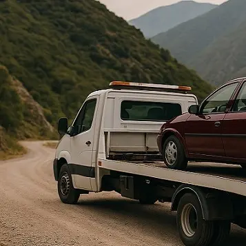 Grúa blanca llevando auto bordo por camino de ripio en Tucumán